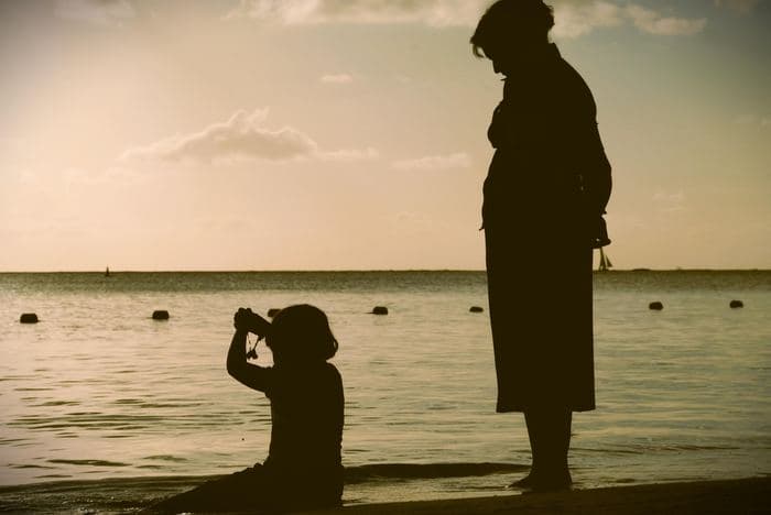 A parent and child looking out together at sunset